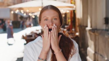 Aman Tanrım, vay canına. Kızıl saçlı genç kız kameraya şaşkın şaşkın bakıyor. Ani zafer, maç kazanma, piyango hedefi başarısı, açık havada iyi haberler. Şehirli kadın güneşli sokakta