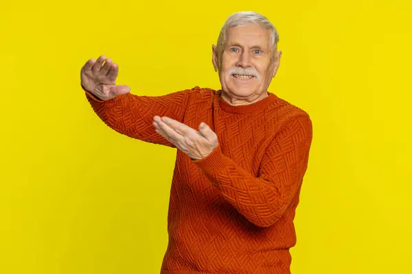 Senior man showing wasting throwing sharing money around, more tips, big profit, winning lottery jackpot, successful shopping payment purchase cashback. Elderly mature grandfather on yellow background