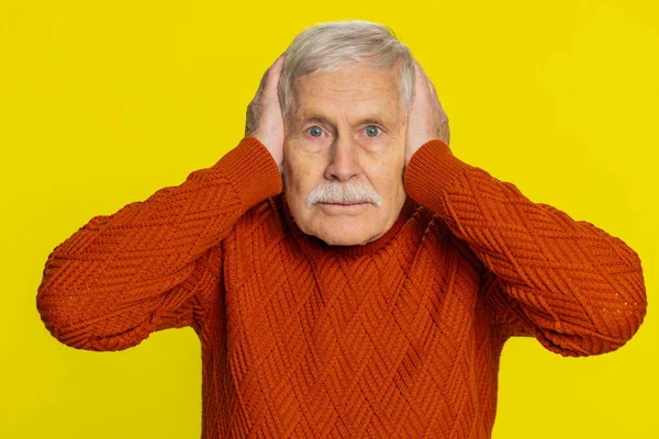 Dont want to hear and listen. Frustrated annoyed irritated elderly old man covering ears gesturing no, avoiding advice ignoring unpleasant noise loud voices. Grandfather isolated on yellow background