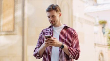 Mutlu, esmer, sakallı, akıllı telefon kullanan internet sosyal medya uygulamasına girip mesaj yazan açık havada sohbet eden bir adam. Şehir caddesinde yürüyen bir turist. Yaşam Tarzları