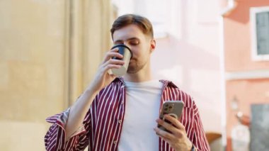 Mutlu esmer, sakallı adam sabah kahvesinin tadını çıkarıyor, sıcak bir şeyler içiyor ve dışarıda gülümsüyor. Dinlenmeye çalışıyorum. Şehirdeki Sunshine Caddesi 'nde yürüyen ve kahve içen bir adam. Dışarıdaki kasaba yaşam tarzları