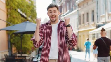 Esmer sakallı mutlu adam bağırıyor, başarıyı kutluyor, kazanıyor, gol başarısı, iyi haber, piyango ikramiyesi, açık havada zafer. Şehirdeki Sunshine Sokağı 'nda yürüyen genç bir adam. Yaşam Tarzları