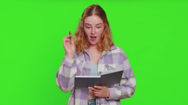 思慮深いジャーナリストの若い女性がノートを作り メモ帳のノートにペンで考えを書き留め リストを作る 良いアイデア 緑色のクロマのキーバックで隔離されたかなり赤毛の学生の少女 — ストック動画
