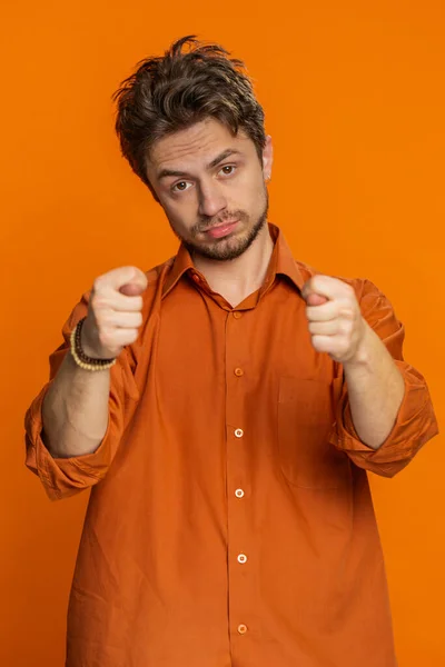 Greedy avaricious Caucasian man showing fig negative gesture you dont get it anyway. Rapacious avaricious acquisitive. Body language. Refusal fig sign. Young guy isolated on orange background indoor