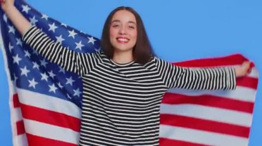 Çizgili bluzuyla gülümseyen beyaz kadın Amerikan bayrağına sarılmış, insan hakları ve özgürlüklerini kutluyor. Bağımsızlık Günü. Stüdyo mavi arka planda kapalı bir kız