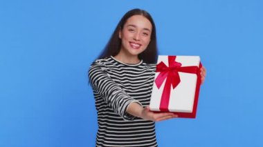 Doğum günü hediyesi sunan olumlu gülümseyen beyaz kadın parti promosyon indirimini kutlamak için hediye paketi uzatıyor. Güzel kız mavi arka planda izole edilmiş