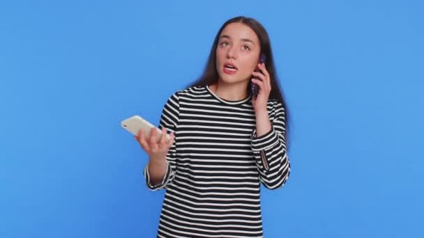 烦躁不安的紧张的白人女人在两个有对话冲突的手机上尖叫着抱怨解决了问题 被蓝色背景隔离的小女孩 — 图库视频影像
