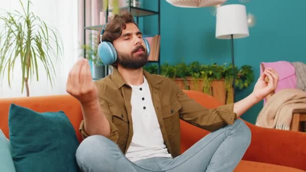 冷静点 放松点听着音乐的中东阿拉伯人深深地吸了口气 闭目沉思 思想集中 心平气和 一个留着胡子的年轻人坐在沙发上的家里客厅里 — 图库视频影像