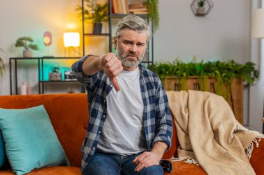 Hoşlanmamak. Oturma odasındaki kanepede oturan gri sakallı, üzgün, olgun bir adamın portresi. Memnuniyetsiz Kafkasyalı yaşlı adam evde hoşnutsuzluğunu ve hoşnutsuzluğunu dile getiriyor.