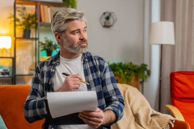 Gündelik giysiler içinde, iş belgelerini analiz eden bilgili, kendinden emin, olgun bir adam mali rapor hazırlıyor. Kafkasyalı yaşlı adam kanepedeki ani zaferle şok oldu.