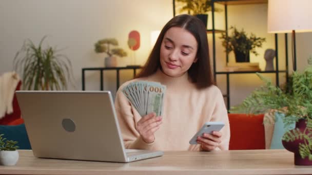 规划预算 有钱的 快乐的白人年轻女子在数钱的时候 用手提电脑计算家里的账单 对收入感到满意的女青年坐在办公室的桌子边攒钱 — 图库视频影像