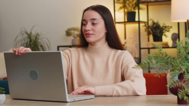 漂亮的女人在办公室完成工作后 坐在沙发上关闭笔记本电脑 年轻的白人女自由职业者在家里的桌子上做远程在线工作 电子学习 在笔记本电脑上浏览互联网 — 图库视频影像
