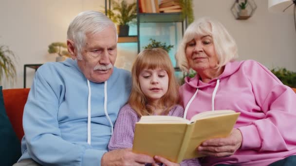 Avós Caucasianos Pequena Neta Lendo Livro Interessante Juntos Sentados Sofá — Vídeo de Stock