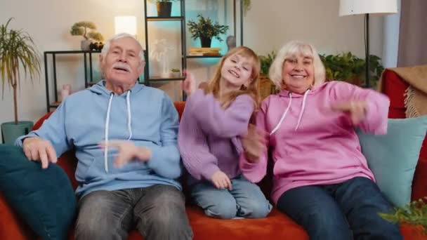快乐兴奋的高加索祖父母和孙女在家里的沙发上跳迪斯科风格的舞 笑着一家人在公寓里共度周末 无忧无虑的自由概念 — 图库视频影像