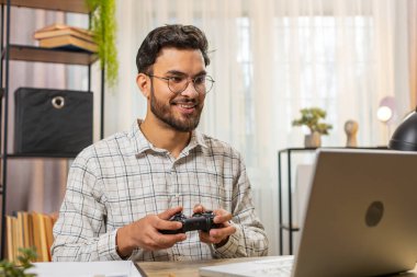 Güzel görünümlü, heyecanlı Hintli işadamı bilgisayar oyununda zaferi kutluyor. Boş zamanlarını ofis masasında geçiriyor. Mutlu İspanyol Serbest Çalışan Video Oyunları Kontrolörü.
