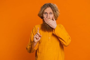 Hiçbir şey söylemeyeceğim. Korkmuş genç adam elleriyle ağzını kapatıyor, kamera karşısında korkmuş görünüyor hayır, korkunç bir sırrı anlatmayı reddediyor inanılmaz bir gerçeği. Turuncu arka plandaki adam