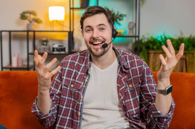 Beni ararsın. Evdeki koltukta oturan mutlu beyaz adam kulaklık takıyor, serbest çalışan, çağrı merkezi, destek servisi operatörü, müşteri ya da iş arkadaşıyla konuşuyor, iletişim desteği...