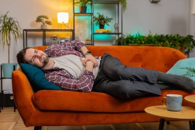 Hasta, genç bir adam kanepeye uzanmış karın ağrısı, mide iltihabı gibi ani ağrılar çekiyor. Sinir hastası, ishal, hazımsızlık, peptik ülser, pankreas hastası.