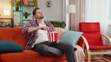 Heyecanlı bir adam patlamış mısır yiyor ve evdeki kanepede oturup ilginç TV dizileri izliyor. Ekose gömlekli mutlu beyaz adam hafta sonu boyunca film izlemekten zevk alıyor.