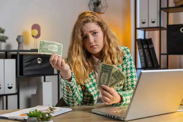 Caucasian young woman freelancer crying counting cash insufficient amount of money. Financial crisis. Bankruptcy. Poverty and destitution. Female girl businesswoman with laptop sitting at home office