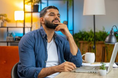 Ev ofisinde dizüstü bilgisayarla otururken akıllı, serbest çalışan genç Hintli bir erkek. Düşünceli İspanyol iş adamı önemli bir yaratıcı proje kararı düşünüyor..