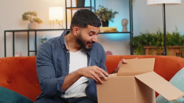 Oturma Odasındaki Kanepede Oturan Heyecanlı Hintli Genç Adam Teslimat Paketini — Stok video