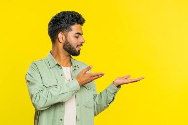 Hintli sakallı adam, aferin diyor ve boş yeri işaret ediyor. Ticari metin fotokopi alanı reklamı için. Adam sarı arka planda izole edilmiş. Yaşam Tarzları