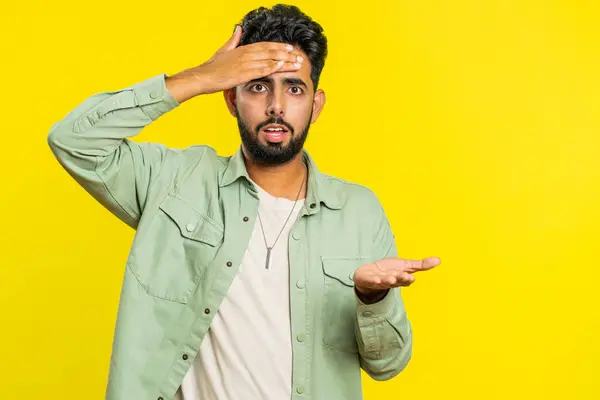 Face palm. Shame on you. Upset sad Indian young man making face palm gesture, feeling bored, disappointed in result, bad news, disagreement, quarrel. Arabian guy isolated on studio yellow background