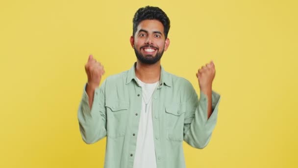成功の勝利を祝う幸せな喜びのインド人男性 誕生日を獲得 宝くじのジャックポットの目標達成ゲーム良い肯定的なニュース 黄色いスタジオの背景に孤立した若いアラビアの男 — ストック動画