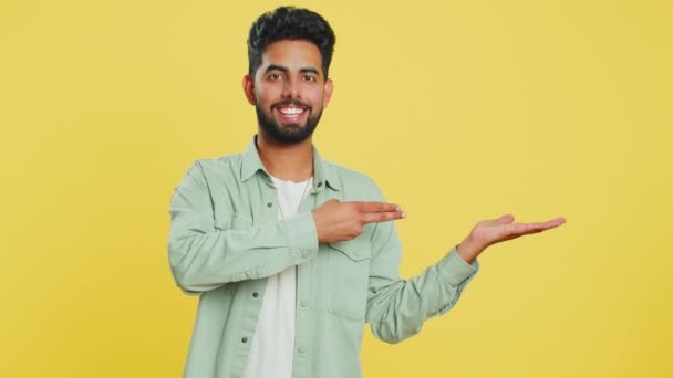 インドのひげ付き男は 商品の宣伝広告のための商業テキストコピースペースのための広告領域 右の空の場所を指す 黄色い背景で孤立した男 ライフスタイル — ストック動画