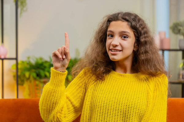 Eureka. Thoughtful clever inspired child girl make gesture raises finger came up with creative plan feels excited with good idea inspiration motivation, question at home apartment. Kid sits on couch
