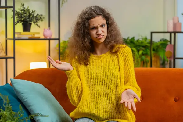 What. Why. Young child kid girl raising hands in indignant expression, asking reason of failure demonstrating disbelief irritation by troubles. Female Caucasian teenager at home in living room on sofa