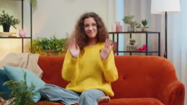 Moda, neşeli, pozitif, 14-15 yaşlarında kız dans ediyor, ritme ayak uyduruyor, el kaldırıyor, dublaj yapıyor. Oturma odasında kanepede oturan Kafkas çocuk.