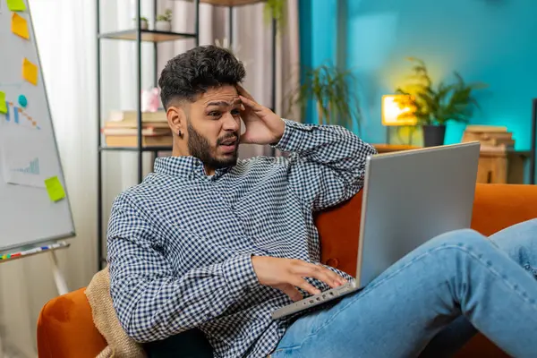 Frustrated Indian man having software problems with laptop angry guy nervous seeing error or mistake notification at computer screen mad employee experience virus attack or app malfunction. Lifestyles