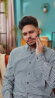 Diş sorunları. Hüsrana uğramış hasta Hintli adam yanağa dokunuyor, gözleri kapatıyor ve diş ağrısına karşı hassas diş çürükleri yüzünden acı çekiyor. İspanyol adam sınıftaki kanepede oturuyor.