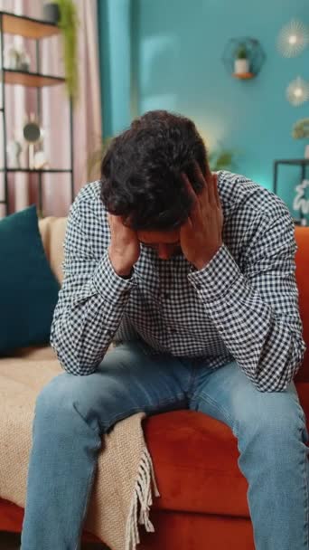 病気のインドの男性は 緊張や片頭痛 ストレス 痛みの悲惨さ 家庭での高血圧に苦しむ頭痛の問題を治療するために寺院をこすります ソファーの部屋にいるヒンドゥーの男 バーティカル — ストック動画