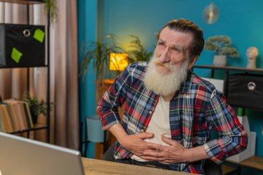 Hayal kırıklığına uğramış Kafkasyalı yetişkin bir adam ofis bilgisayarında çalışırken aşırı yemek yiyor. Üzgün iş adamı büyükbaba karnına dokunuyor ve rahatsız ve keskin bir acı hissediyor..