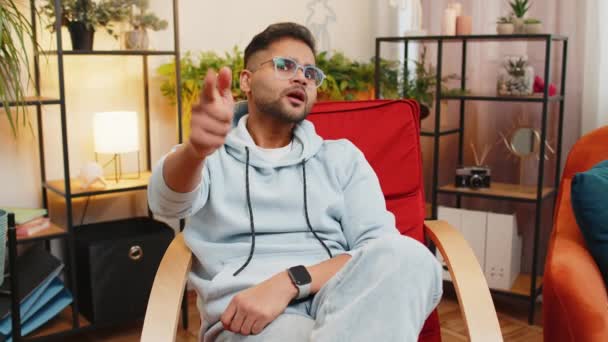 どうした 厳格な不幸なインド人男性は カメラに手指を指し 怒って選択し 有罪判決を下し 疑わしいことに気づき 自宅の部屋のアパートで間違いを訴えました 男は椅子に座る — ストック動画