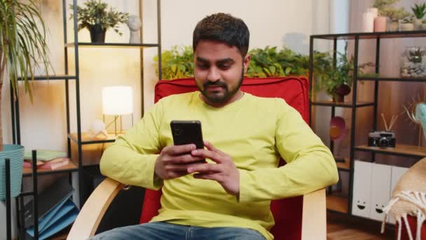 Indiase Man Zit Stoel Maakt Gebruik Van Mobiele Telefoon Glimlacht — Stockvideo