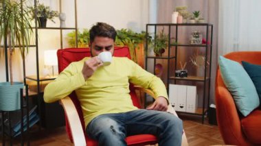 Çekici, gülümseyen Hintli bir adam bir fincan sıcak kahve ya da bitki çayı içerken sabahları sallanan bir sallanan sandalyede oturuyor. Arap adam rahat rahat dinleniyor, dinleniyor, mola veriyor.