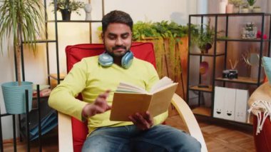 Hintli adam ilginç kitaplar okuyor, sayfaları çevirip gülümsüyor edebiyattan zevk alıyor, rahat koltukta dinleniyor. Huzurlu, neşeli bir adamın portresi. Oturma odasında dinleniyor. Sandalyede.