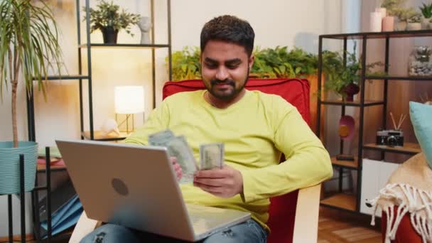 プランニング予算 お金の現金を数える金持ちの幸せなインド人男性は ラップトップコンピュータを使用して 家庭の請求書を計算します アラビアの男は収入に満足し 計画された休暇 ギフトのためのお金を節約します — ストック動画