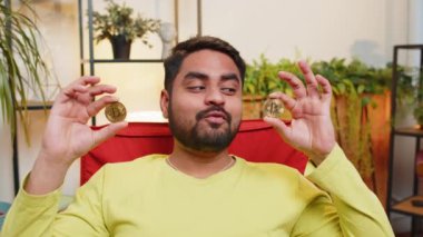 Hintli adam iki altın sikke tutuyor, başarılı geliştirici programcı. Hisse senedi tüccarı, online ticaret operasyonlarını izledikten sonra bitcoin kazanıyor. Artan zenginlik, artan mali refah