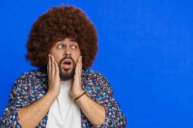 Aman Tanrım, vay canına. Afro saç stili peruklu, hayret verici kazanan adam büyük gözlerle kameraya bakıp başarıyı kutlayan iyi haberlere şaşırdı. Mavi arka plandaki adam. Kopyalama alanı