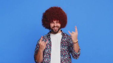 Coşkulu, mutlu, beyaz bir adam rock 'n roll jesti sergiliyor. Havalı bir tabela, çılgın bir ifadeyle evet diye bağırıyor. Dans ederek zafer kazanıyor. Mavi arka planda izole edilmiş şık genç adam.
