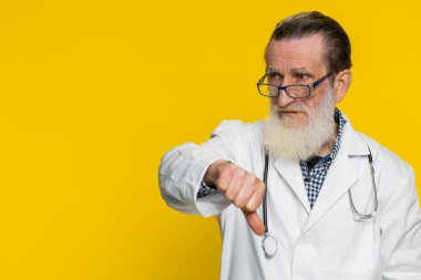 Hoşlanmamak. Mutsuz kıdemli doktor kardiyolog, olumsuz tepkileri onaylamadığını işaret ediyor. Sarı arka planda eczacı dedesi. Kopyalama alanı