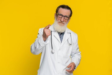 Kıdemli doktor kardiyolog parmağını sallıyor ve hayır diyor, dikkatli ol, tehlike hatasından uzak dur tavsiyesi, onaylanmama işareti, anlaşmazlığa karşıt görüş. Sarı arka planda eczacı dedesi.
