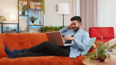 Laptop kullanan bir sürü şaşırmış Hintli iyi haber aldı. Aniden kazanılan piyango ikramiyesini kutlarken şok oldu. Netbook 'lu neşeli İspanyol adam evdeki oturma odasında kanepede oturuyor..