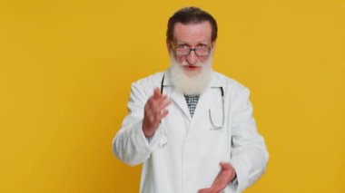 Kıdemli doktor kardiyolog parmağını sallıyor ve hayır diyor, dikkatli ol, tehlike hatasından uzak dur tavsiyesi, onaylanmama işareti, anlaşmazlığa karşıt görüş. Sarı arka planda eczacı dedesi.