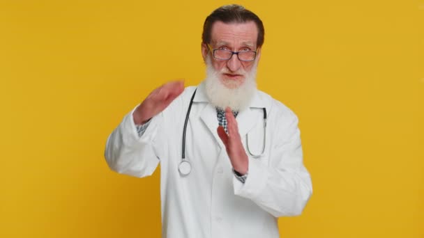 疲惫的老年心脏病医生老人表现出暂停的姿态 限制或停止的迹象 在黄色背景下被隔离的药剂师祖父 — 图库视频影像
